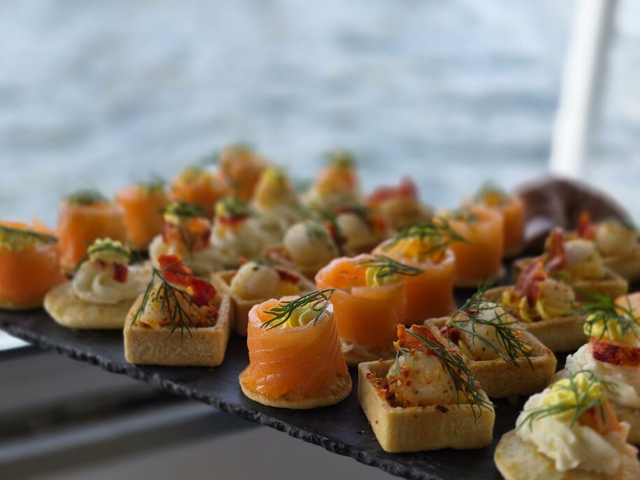 Canapés au saumon et tartelettes garnies sur une ardoise, la Seine au fond